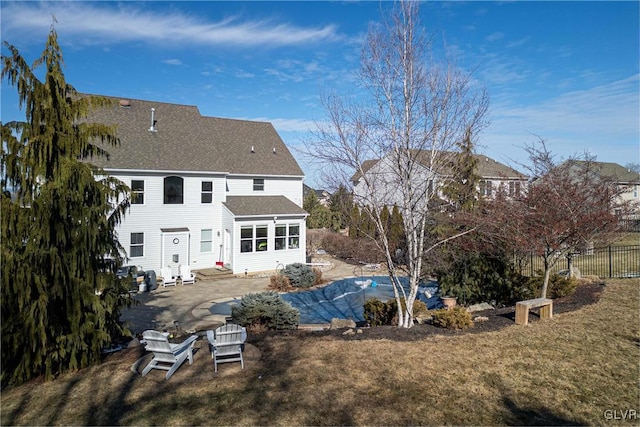 rear view of property featuring a pool, a lawn, and a patio