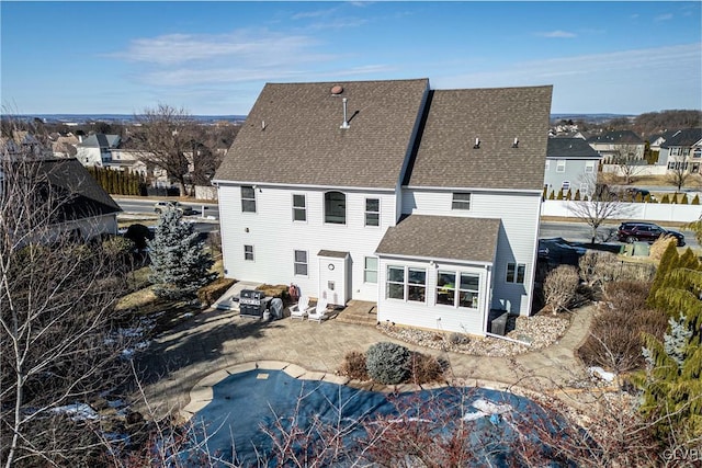 rear view of property featuring a covered pool and a patio area