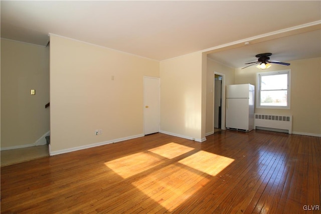 empty room with hardwood / wood-style flooring, ceiling fan, and radiator