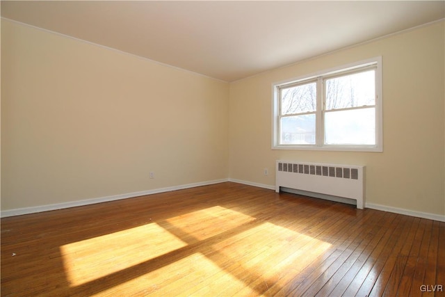 spare room featuring radiator and hardwood / wood-style floors