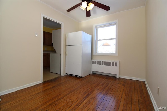 unfurnished room with dark wood-type flooring, ceiling fan, radiator heating unit, and crown molding