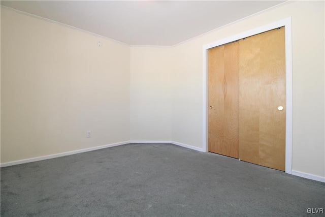 unfurnished bedroom featuring crown molding, dark carpet, and a closet