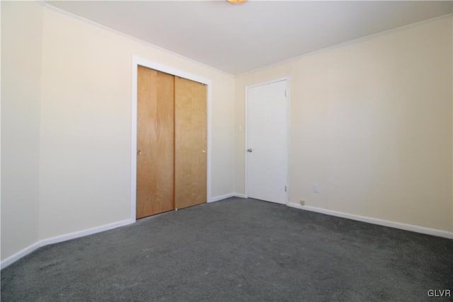 unfurnished bedroom featuring dark colored carpet, crown molding, and a closet