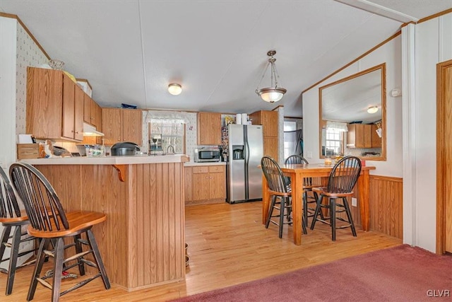 kitchen featuring light hardwood / wood-style floors, stainless steel appliances, kitchen peninsula, and wood walls