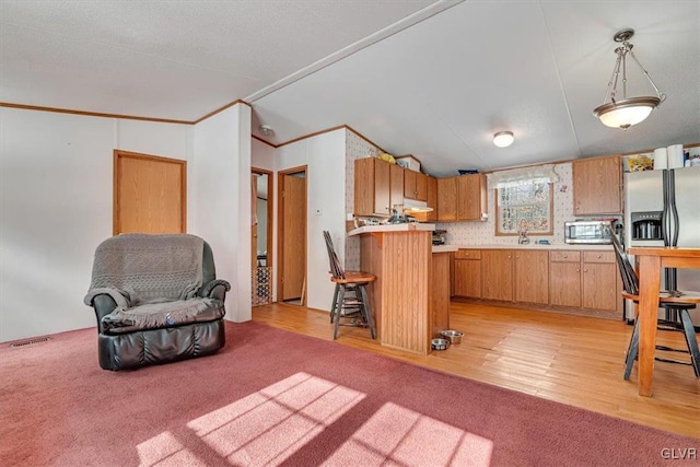 kitchen with light carpet, a kitchen breakfast bar, kitchen peninsula, pendant lighting, and stainless steel appliances