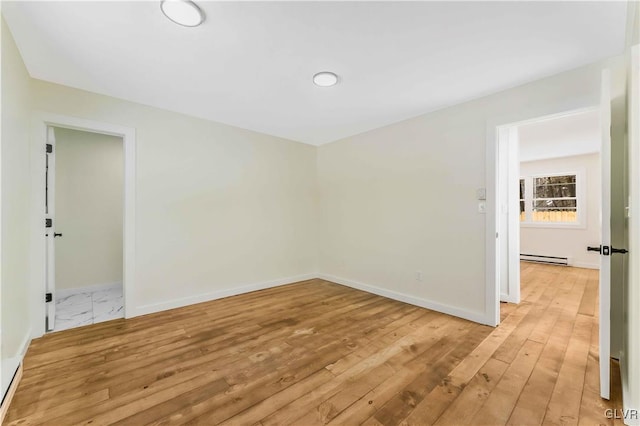 empty room with a baseboard radiator and light hardwood / wood-style flooring