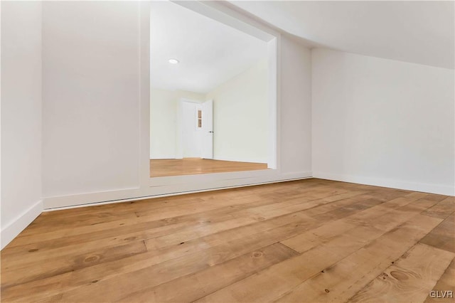 unfurnished room featuring hardwood / wood-style flooring and lofted ceiling