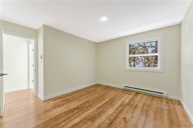 empty room featuring baseboard heating and light hardwood / wood-style floors