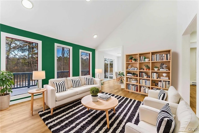 living room with a baseboard radiator, high vaulted ceiling, and light hardwood / wood-style flooring