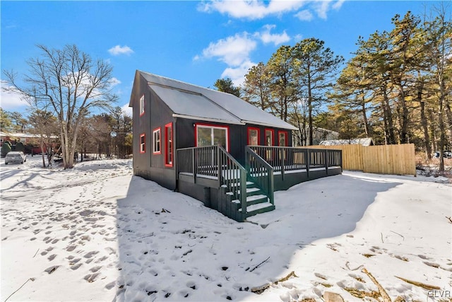 snow covered rear of property featuring a wooden deck