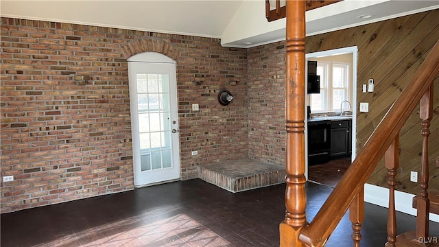 foyer entrance with vaulted ceiling, brick wall, dark hardwood / wood-style flooring, and sink