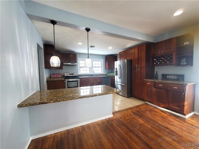 kitchen with dark stone countertops, stainless steel appliances, light hardwood / wood-style floors, decorative light fixtures, and kitchen peninsula