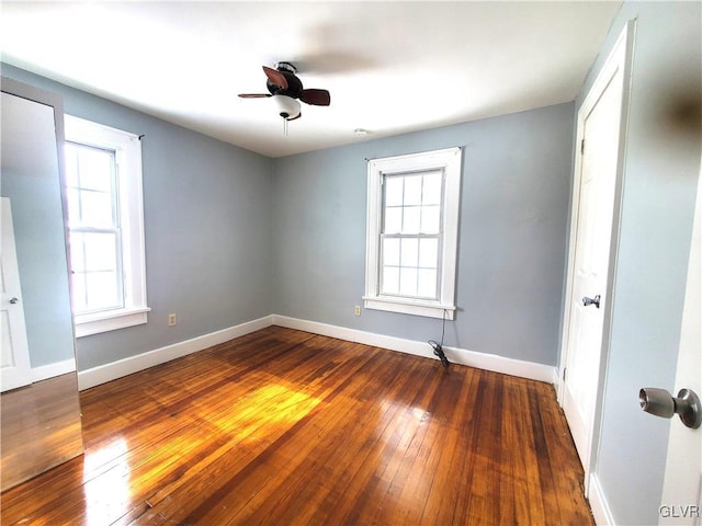 unfurnished room featuring ceiling fan, a wealth of natural light, and dark hardwood / wood-style flooring