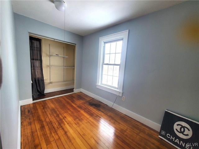 unfurnished bedroom with dark hardwood / wood-style flooring and a closet