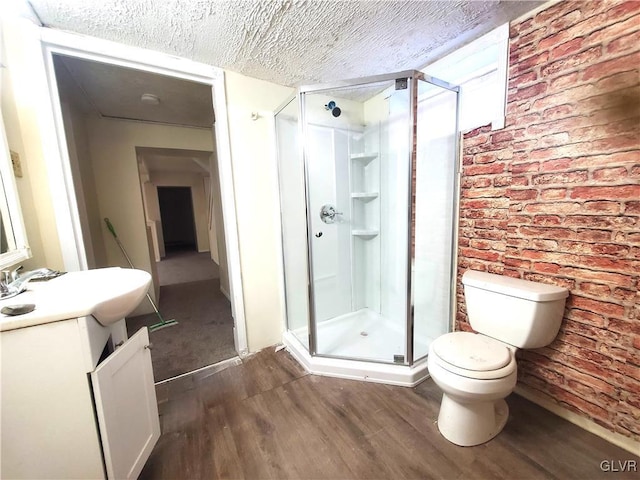 bathroom with toilet, a textured ceiling, vanity, a shower with door, and hardwood / wood-style floors