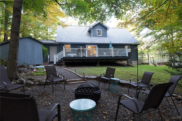 rear view of house with a yard, a deck, and an outdoor fire pit