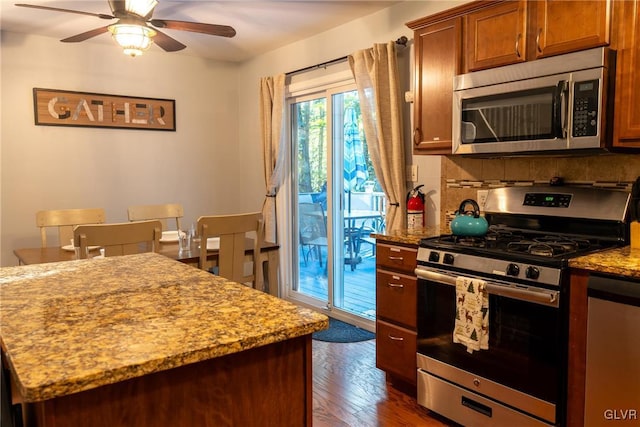 kitchen with ceiling fan, appliances with stainless steel finishes, dark hardwood / wood-style floors, tasteful backsplash, and light stone countertops