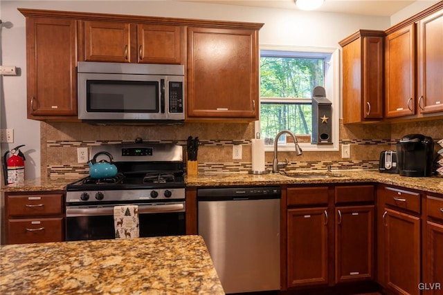 kitchen featuring light stone counters, appliances with stainless steel finishes, sink, and decorative backsplash