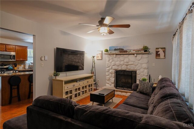 living room with sink, a fireplace, light hardwood / wood-style floors, and ceiling fan