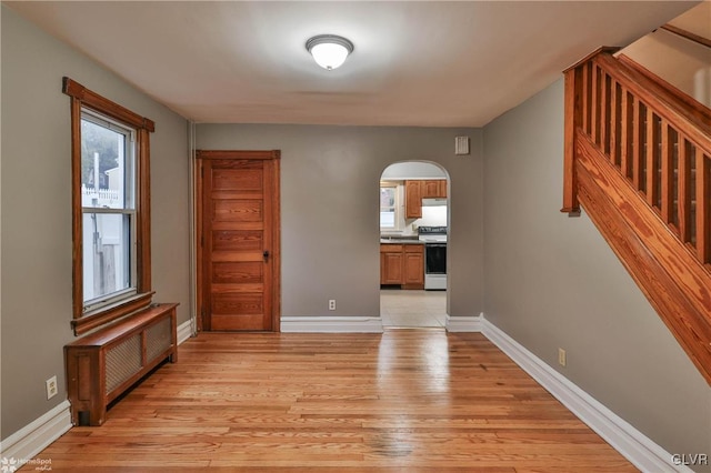 interior space with radiator heating unit, a wealth of natural light, and light wood-type flooring