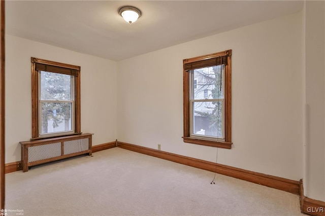 empty room with radiator, plenty of natural light, and light colored carpet