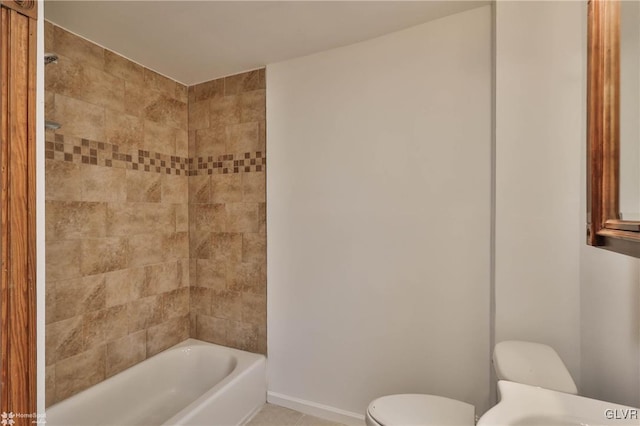 bathroom with tile patterned flooring, tiled shower / bath, and toilet