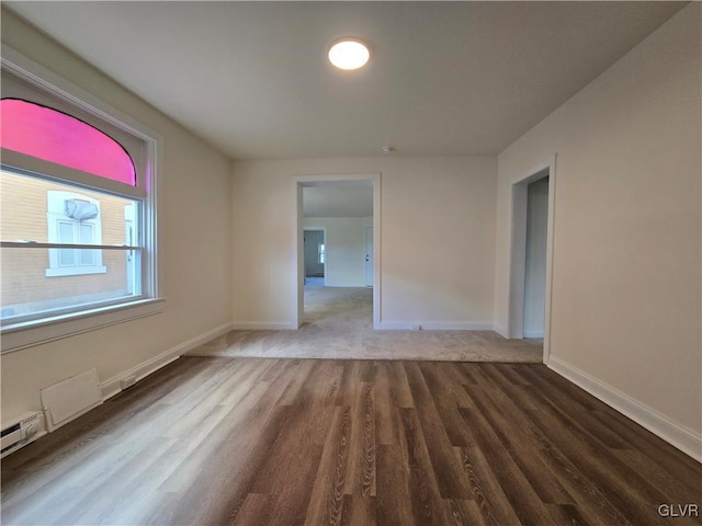 unfurnished room featuring hardwood / wood-style flooring and baseboard heating