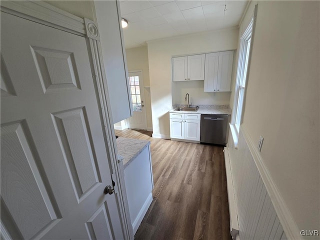 kitchen featuring hardwood / wood-style flooring, sink, stainless steel dishwasher, and white cabinets