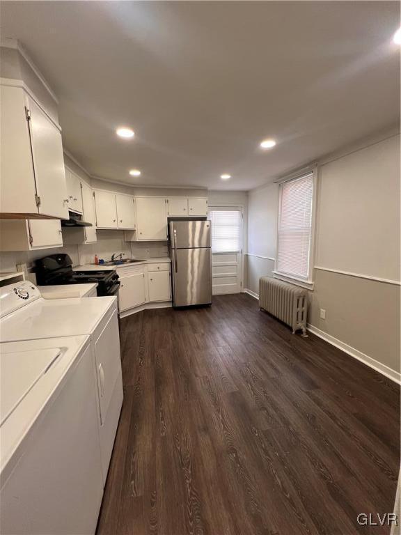 kitchen featuring radiator, white cabinets, stainless steel fridge, electric range, and washing machine and dryer