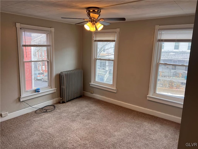 carpeted empty room with ceiling fan and radiator heating unit