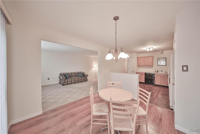 dining area featuring sink, an inviting chandelier, and light hardwood / wood-style flooring