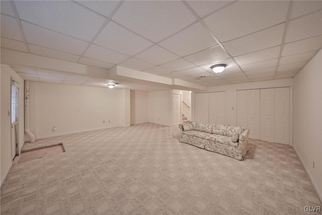 interior space with a paneled ceiling and light carpet