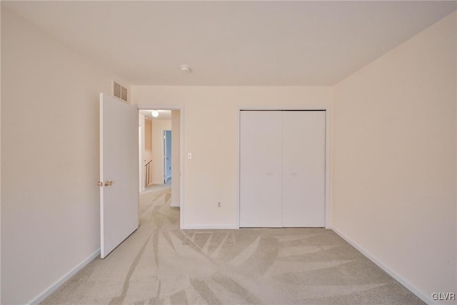 unfurnished bedroom featuring light carpet and a closet