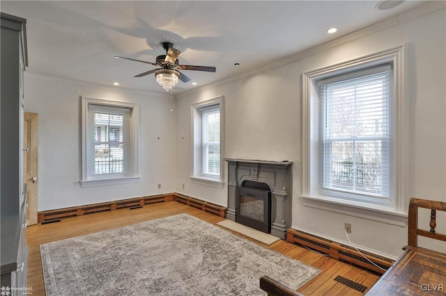 living room featuring hardwood / wood-style flooring, ornamental molding, a baseboard radiator, and ceiling fan