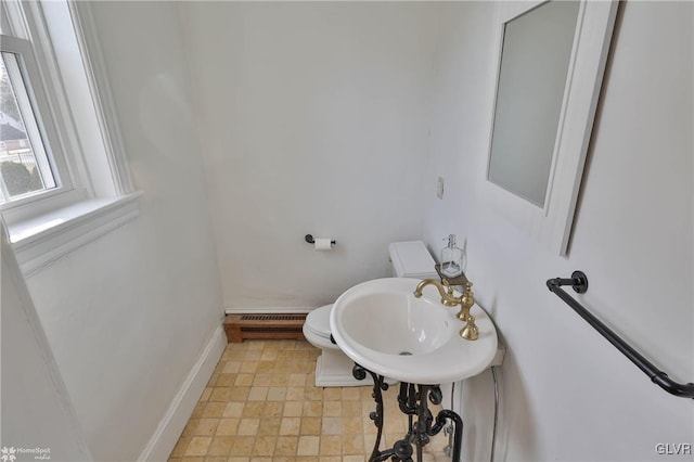 bathroom featuring sink, a baseboard heating unit, and toilet