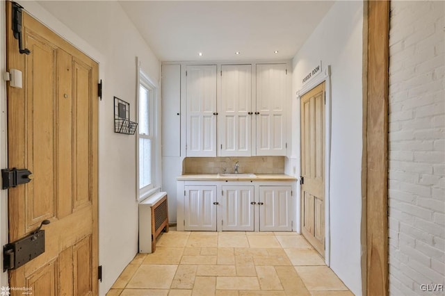 interior space with sink, radiator, and decorative backsplash