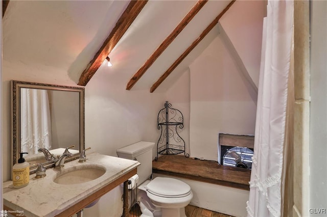 bathroom featuring sink, toilet, and vaulted ceiling with beams