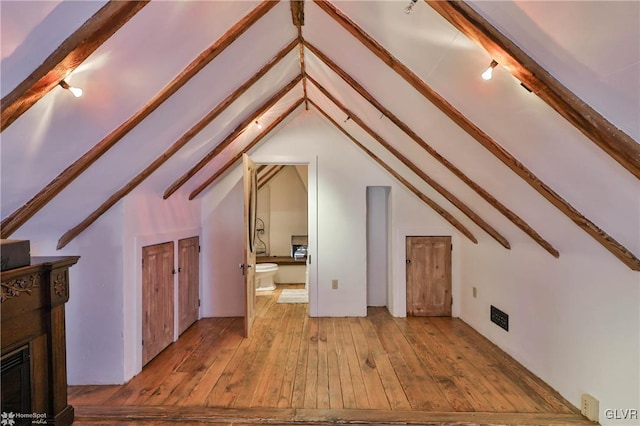 interior space with light hardwood / wood-style flooring and lofted ceiling with beams