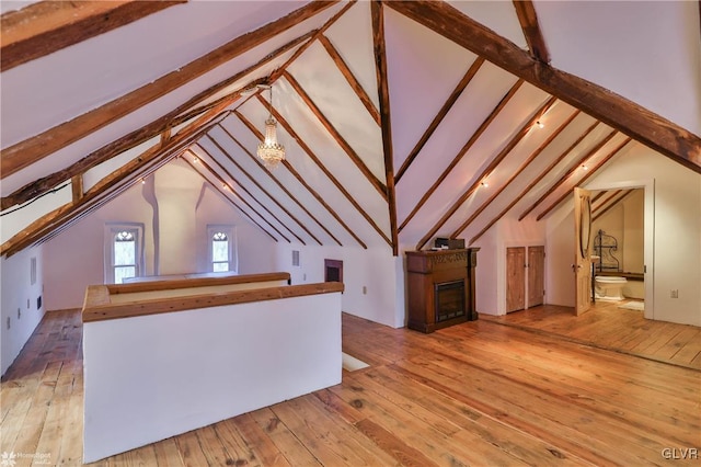 additional living space featuring light wood-type flooring and lofted ceiling with beams