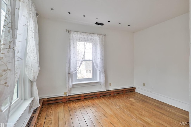 empty room with light hardwood / wood-style floors and baseboard heating