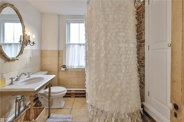 bathroom featuring tile patterned flooring, toilet, a baseboard radiator, tile walls, and sink