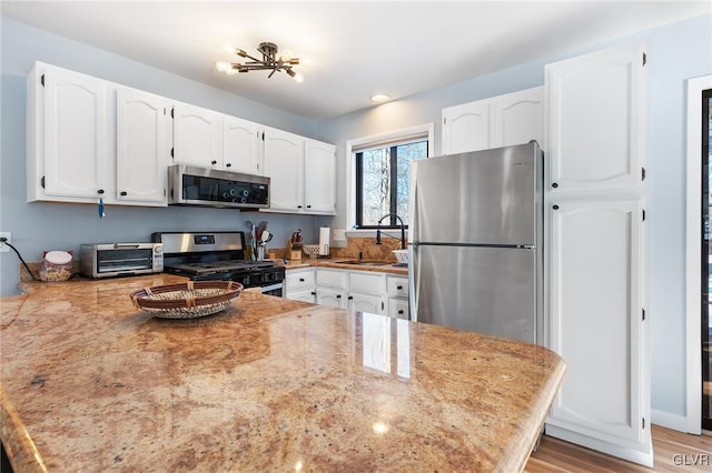 kitchen with stainless steel appliances, sink, white cabinets, and kitchen peninsula