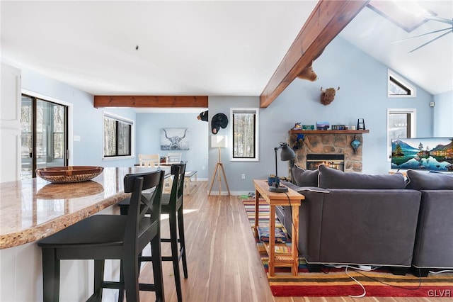 living room featuring wood-type flooring, vaulted ceiling with beams, and a fireplace