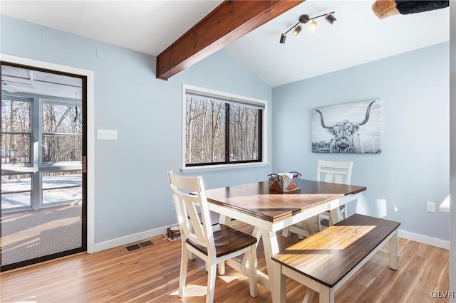 dining space with light hardwood / wood-style floors and vaulted ceiling with beams