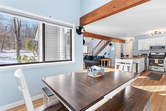 dining room with beam ceiling and light hardwood / wood-style floors