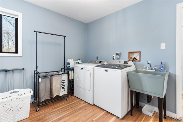 clothes washing area featuring washer and clothes dryer and light hardwood / wood-style flooring