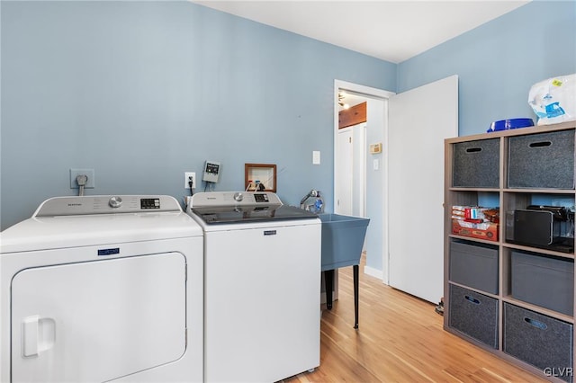 washroom featuring washing machine and clothes dryer and light hardwood / wood-style flooring