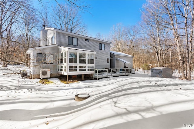 snow covered property featuring a storage shed, a deck, a sunroom, and ac unit