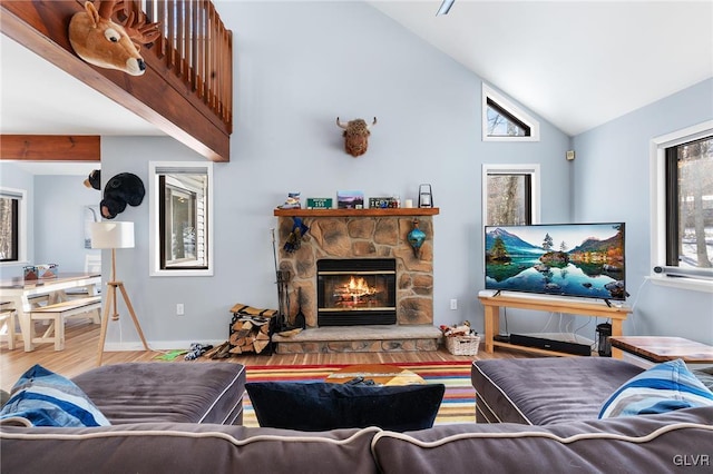 living room featuring hardwood / wood-style floors, a stone fireplace, plenty of natural light, and high vaulted ceiling