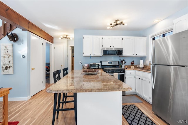 kitchen featuring a kitchen island, appliances with stainless steel finishes, a breakfast bar area, and white cabinets